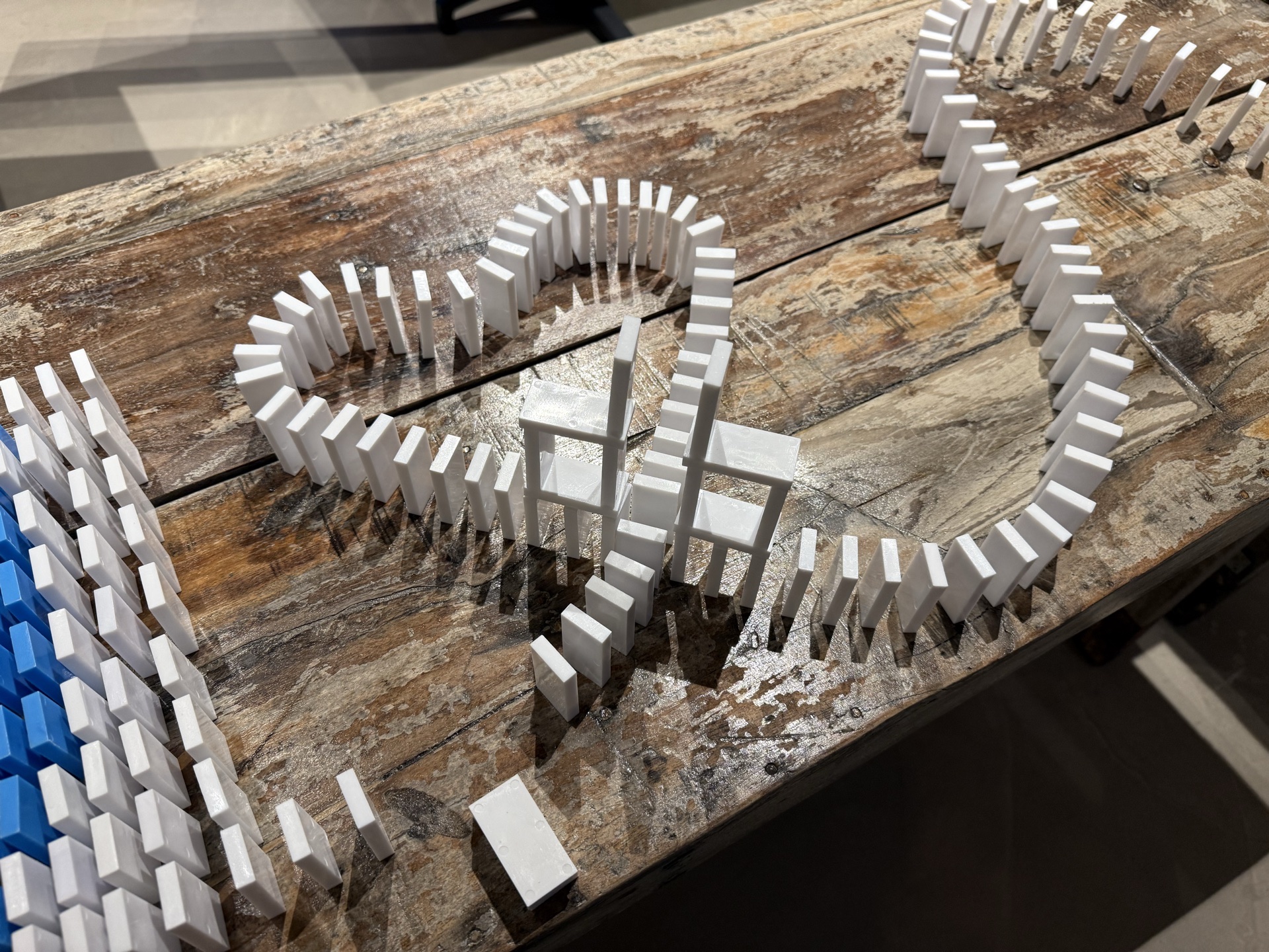 Nahaufnahme einer komplexen Dominostrecke mit kunstvollen Kurven und Verzweigungen auf dem Boden